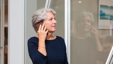 Een collega staat naast een vergaderkamer en is aan het telefoneren