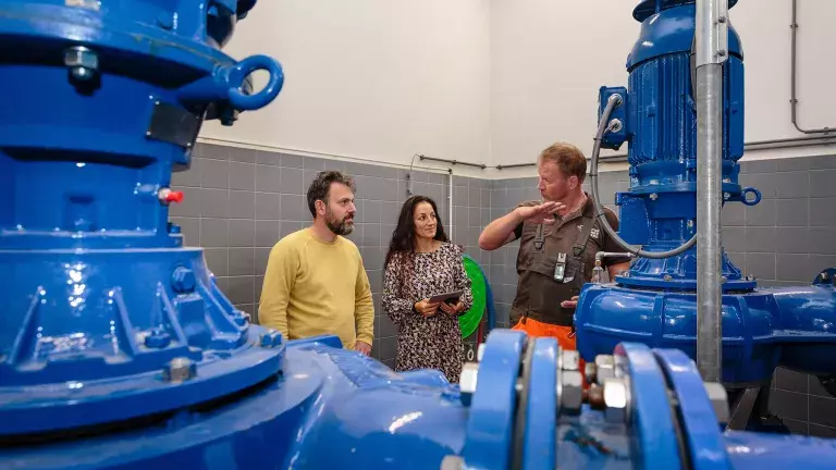 Twee collega's krijgen uitleg over het gemaal van een andere collega
